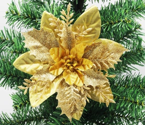 Detailed view of a multi-layer gold Christmas flower with glitter on a green tree branch