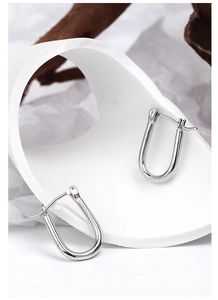 Artistic layout of minimalist silver U-shaped horseshoe earrings on textured background