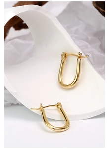 Close-up of gold-plated U-shaped horseshoe earrings on minimalist white background