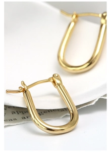 Macro detail of gold-plated U-shaped horseshoe earrings with high-shine metallic finish
