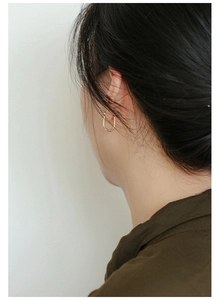 Close-up of minimalist gold U-shape horseshoe earring worn by a model in a side view