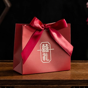 Detail of red wedding candy box with golden foil lettering and elegant ribbon handle