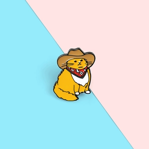 Detailed view of an orange cowboy cat enamel pin with brown hat and red neckerchief