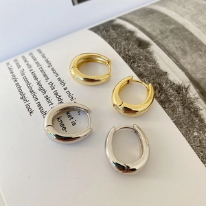 Detail of wide hoop earrings in gold and silver finish with a polished mirror texture