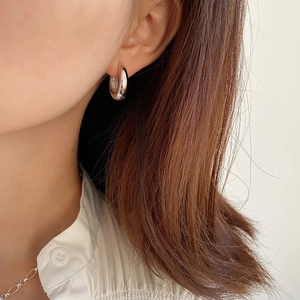 Close-up of minimalist 925 sterling silver wide arc hoop earring worn by a model