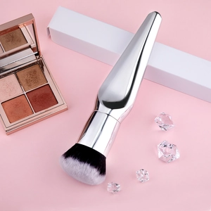 Detail view of a large silver foundation brush with dual-tone bristles and makeup accessories