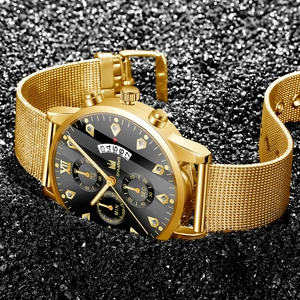 Détail macro d'une montre dorée à bracelet maille avec cristaux et guichet de date