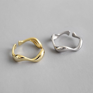 Detailed view of irregular wavy open rings in gold and silver with polished finish
