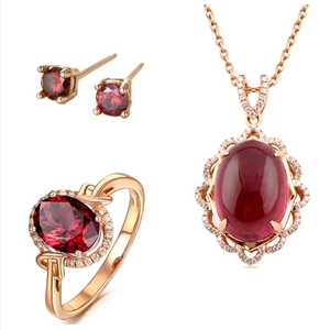 Rose gold jewelry set with pigeon blood red ruby necklace, earrings, and ring on white background