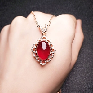 Close-up of a ruby pendant on a rose gold necklace worn by a model in soft lighting