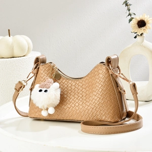Dettaglio della trama intrecciata su borsa kaki con ciondolo di peluche e finiture in oro lucido