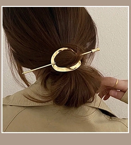 Detail view of a minimalist gold hollow oval hair pin styled on a woman's bun