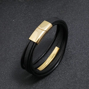 Detail of multi-layer black leather bracelet with magnetic gold metal clasp and trim