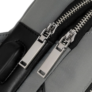 Close-up of grey oxford fabric and black leather trim with dual metal zippers on chest bag
