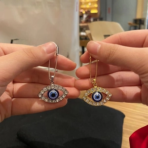 Detailed macro view of gold and silver evil eye safety pin earrings with crystals