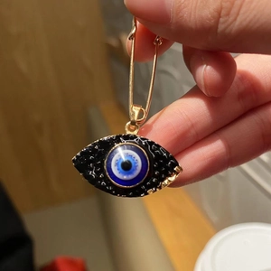 Golden Evil Eye fashion brooch featuring deep blue enamel inlay held by hand
