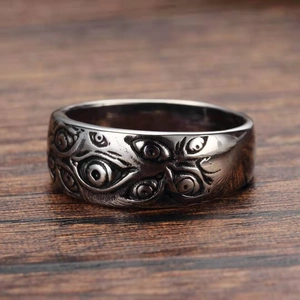 Close-up of vintage silver Evil Eye ring featuring gothic embossed eye motifs on wood