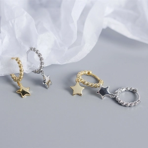 Detail of S925 sterling silver beaded hoop earrings with hanging star charms in gold and silver