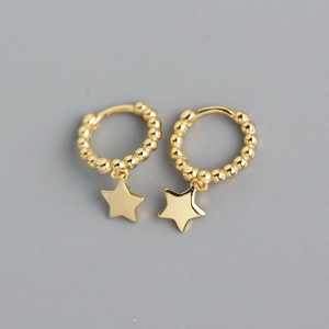 Detailed macro view of gold hoop earrings with small beads and star shaped pendants