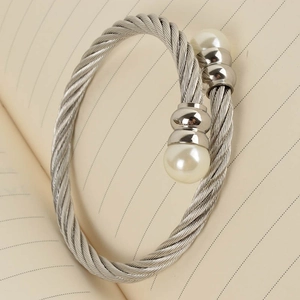 Detailed macro view of a twisted cable bangle featuring two elegant white pearls at each end