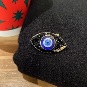 Luxury blue Evil Eye brooch with rhinestones and gold alloy on black fabric background