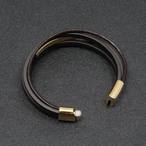 Close-up of brown and black leather braided bracelet with a golden magnetic clasp