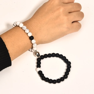 Detail of couple bracelets with white turquoise and black obsidian beads and magnetic charm