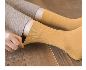 Detailed view of elastic ginger yellow ribbed cotton socks on wooden floor