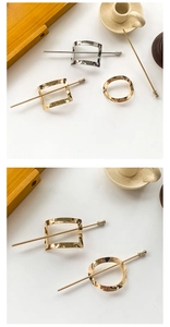 Detail of geometric metal hair pins in gold and silver finish on a wooden tray