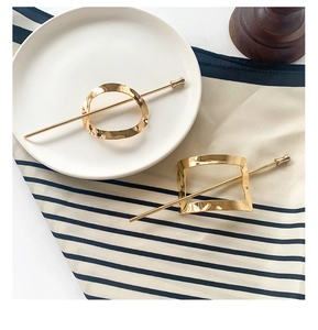 Detailed view of geometric golden hair sticks with irregular circular and square designs