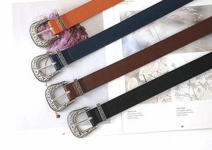 Flat lay of vintage carved belts in orange, navy, brown, and black with silver buckles