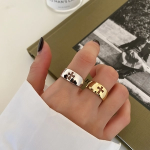 Detailed view of silver and gold wide rings with cutout cross design on female hand