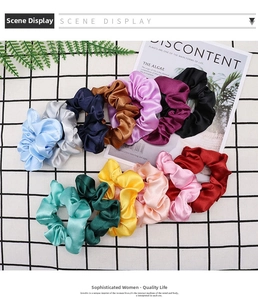 Flat lay of 12 colorful satin scrunchies with glossy texture on checkered background