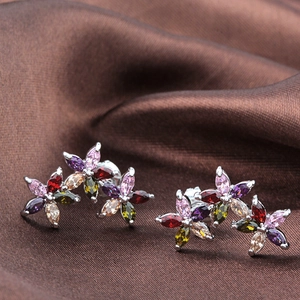 Macro shot of silver floral stud earrings with multi-colored marquise zirconia on brown silk