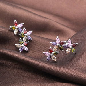Macro shot of silver flower earrings with colorful AAA marquise zircons on brown satin fabric
