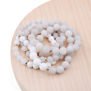 Close-up of bohemian layered beaded bracelets with white turquoise and gold metal discs