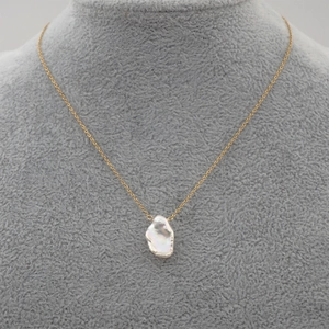 Baroque pearl necklace on a gold chain displayed on a professional grey jewelry bust