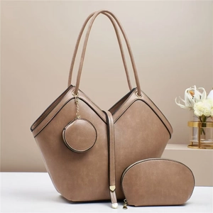 Three-piece brown PU leather tote bag set with round charm and crescent clutch on display