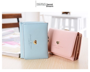 Close-up of short tri-fold wallets in pastel blue and pink with golden heart clasp