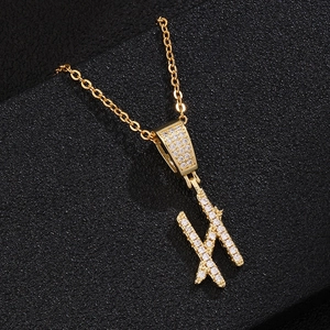 Close-up of golden letter H pendant with pave-set zircons on a sturdy cross chain
