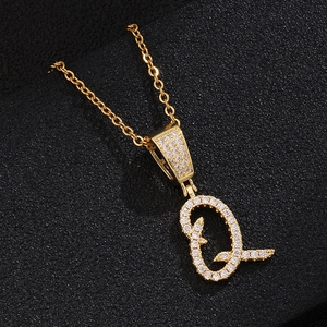 Detailed view of golden letter Q pendant featuring sparkling pavé zircons on black background