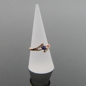 Dettaglio dell'anello a fiore in oro rosa con gemma blu su supporto bianco