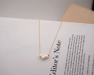 Detail of elegant gold necklace with freshwater pearls and beads on an open book page