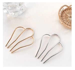 Close-up of minimalist M-shaped gold and silver metal hair forks for French braided styles