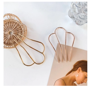 Detail shot of elegant U-shaped gold and rose gold metal hair pins on a magazine