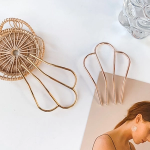 Elegant M-shaped metal hair forks in gold and rose gold with a minimalist shell design