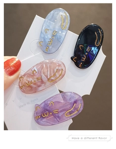 Set of four cute cat-shaped hair clips in marble and glitter finishes on a display card