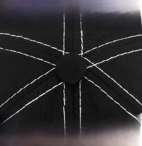 Detail of black cotton baseball cap showing white contrast stitching and top button