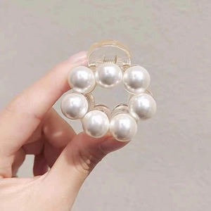 Close-up of elegant hair claw clip with seven round white pearls on clear acrylic base
