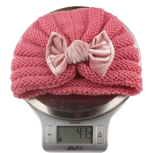 Detail showing the 41.3g lightweight velvet bow baby hat on a weighing scale